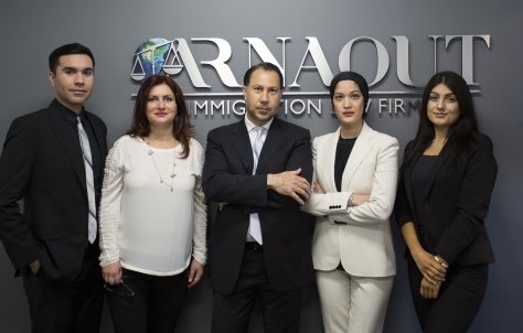 The lawyers at Arnaout Immigration Law Firm standing in front of their signage at their office.